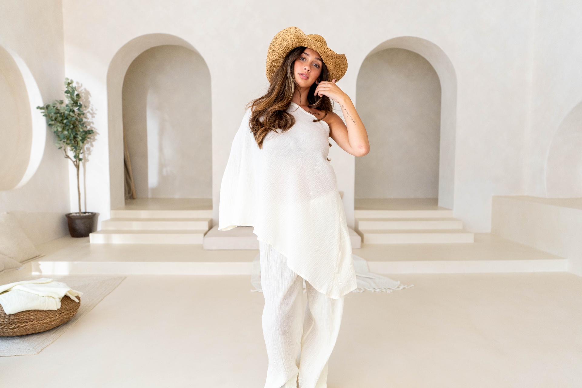 Model in straw hat lounging in resortwear