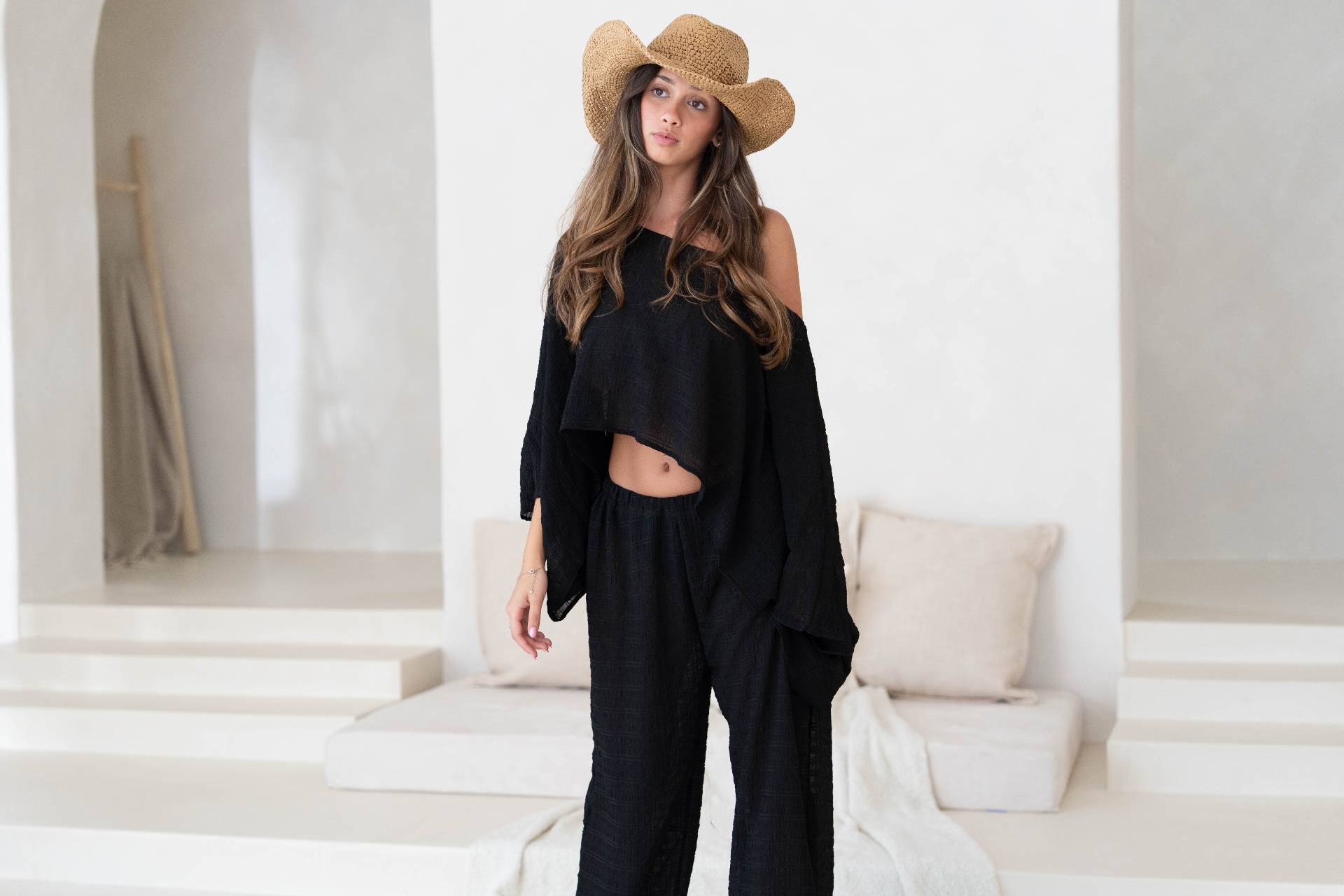 Model in black linen co-ord and straw hat